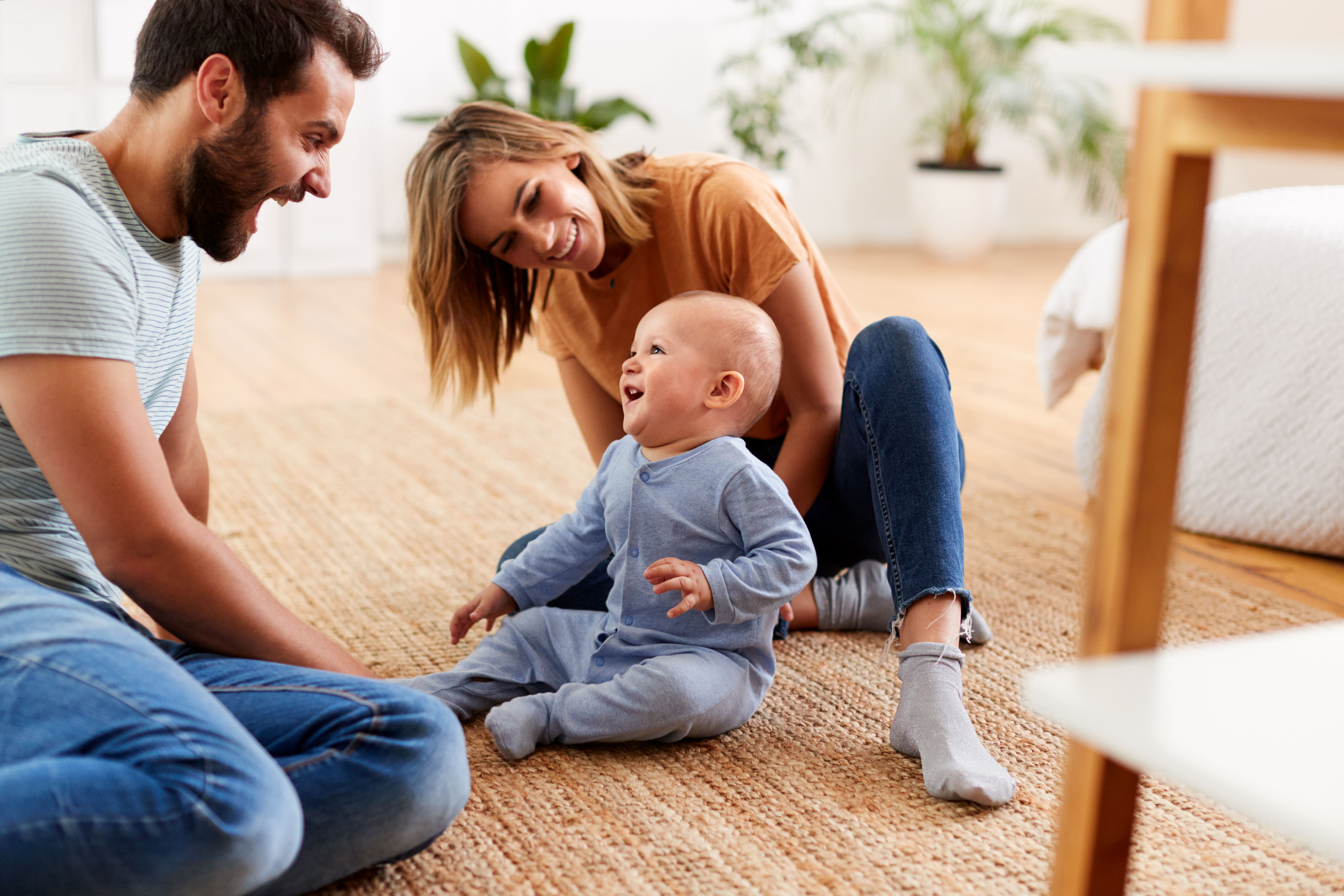 Parents Sitting On Floor At Home Playing With Baby Son