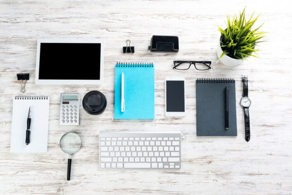 A neatly organized desk of items including a keyboard, notepad, and tablet.